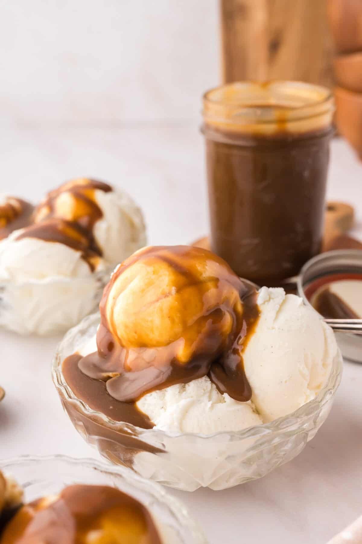Bowl of vanilla ice cream topped with butterscotch sauce.