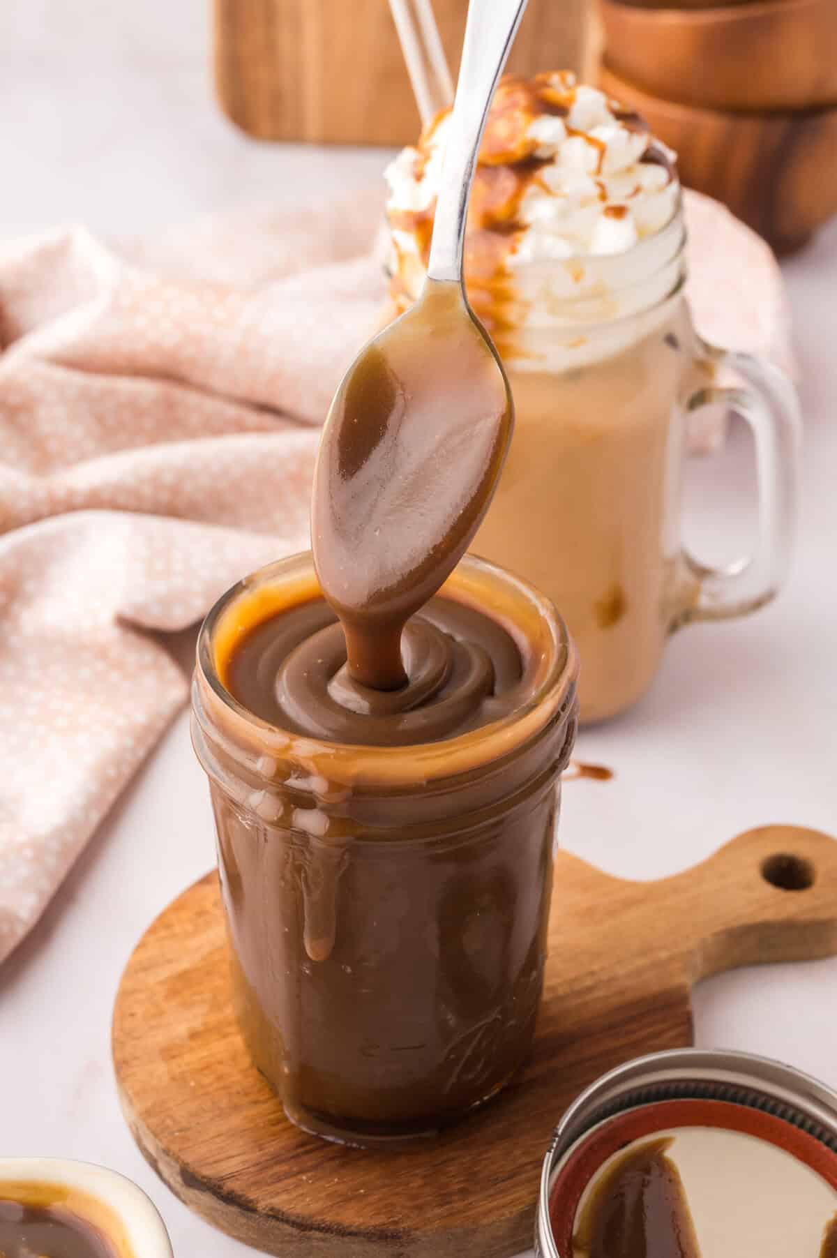 Homemade butterscotch sauce being drizzled off of spoon into a jar.