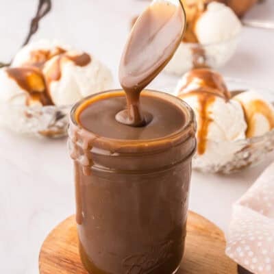 Butterscotch sauce dripping off a spoon over a mason jar.