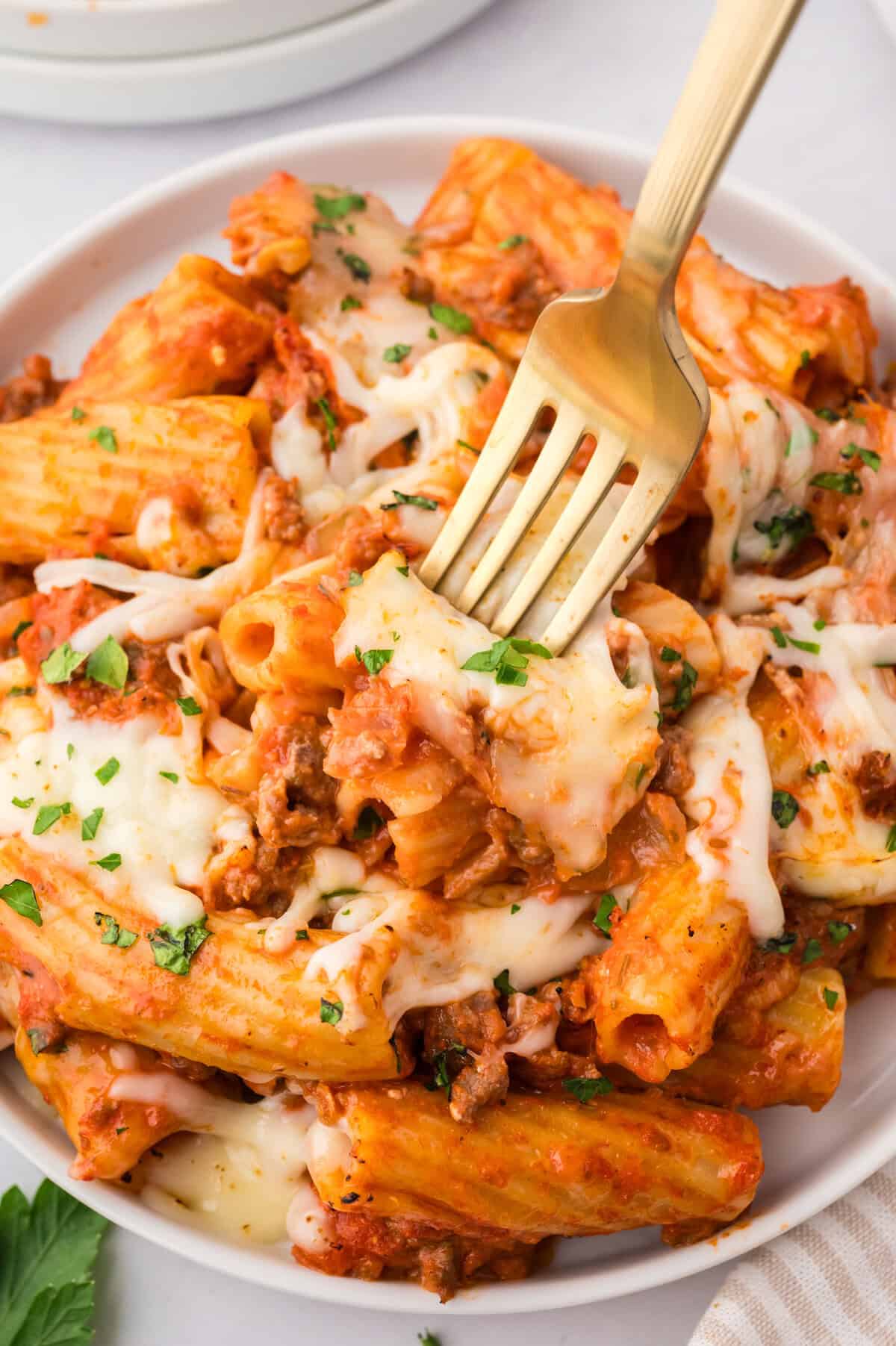 Fork in plate full of baked rigatoni.