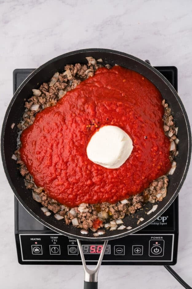 Ground beef, pasta sauce, and cream cheese in skillet.