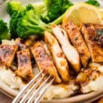 Sliced chicken breast on plate with mashed potatoes and broccoli.