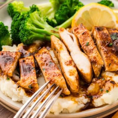 Sliced chicken breast on plate with mashed potatoes and broccoli.