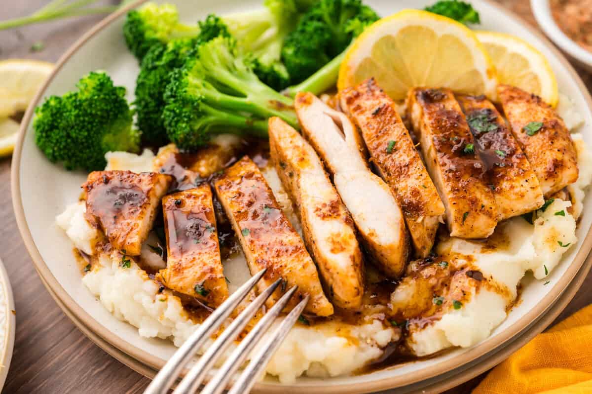 Sliced chicken breast on plate with mashed potatoes and broccoli.