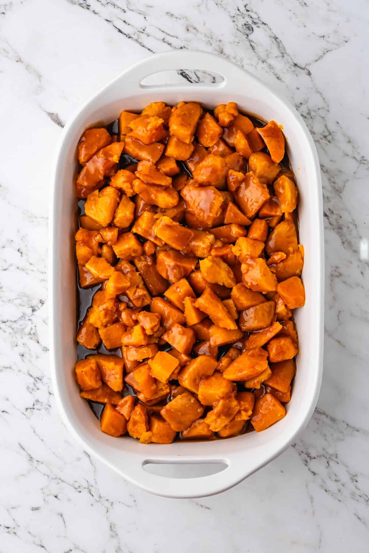 Brown sugar glaze poured over canned yams in casserole dish.