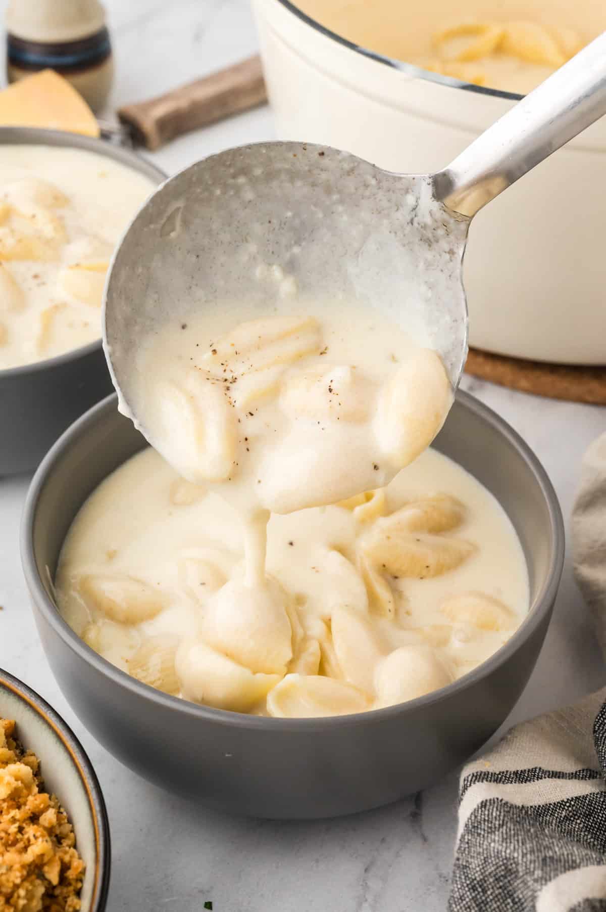 Mac and cheese soup recipe being ladled inot bowl.
