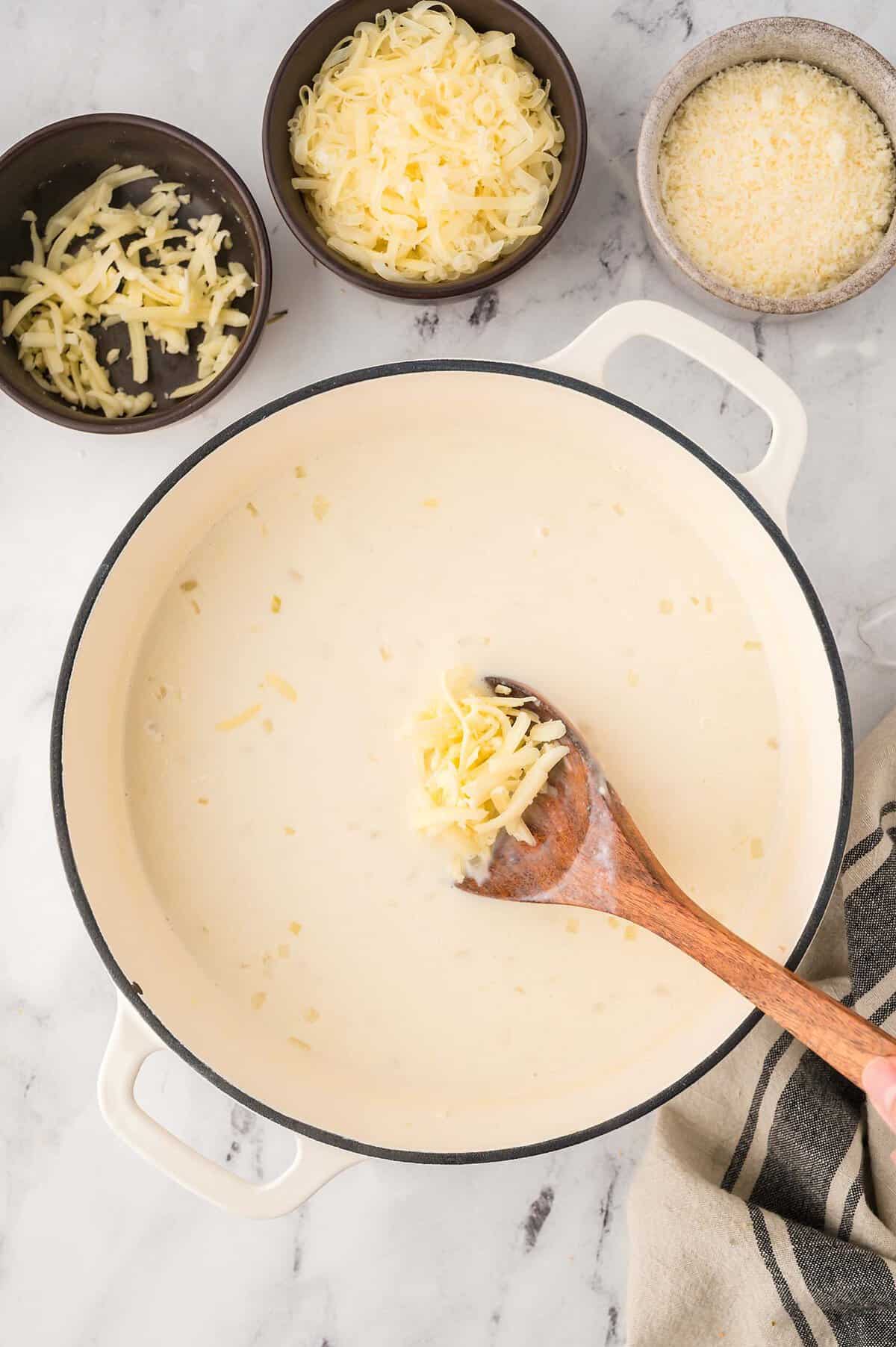 Cheese being stirred into pot of soup.