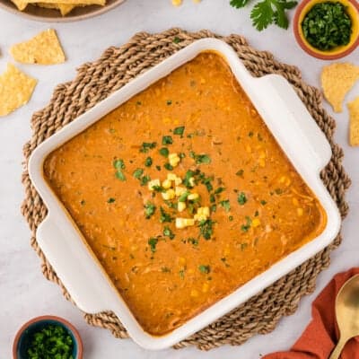 Chicken enchilada dip in white baking dish topped with extra corn and cilantro.