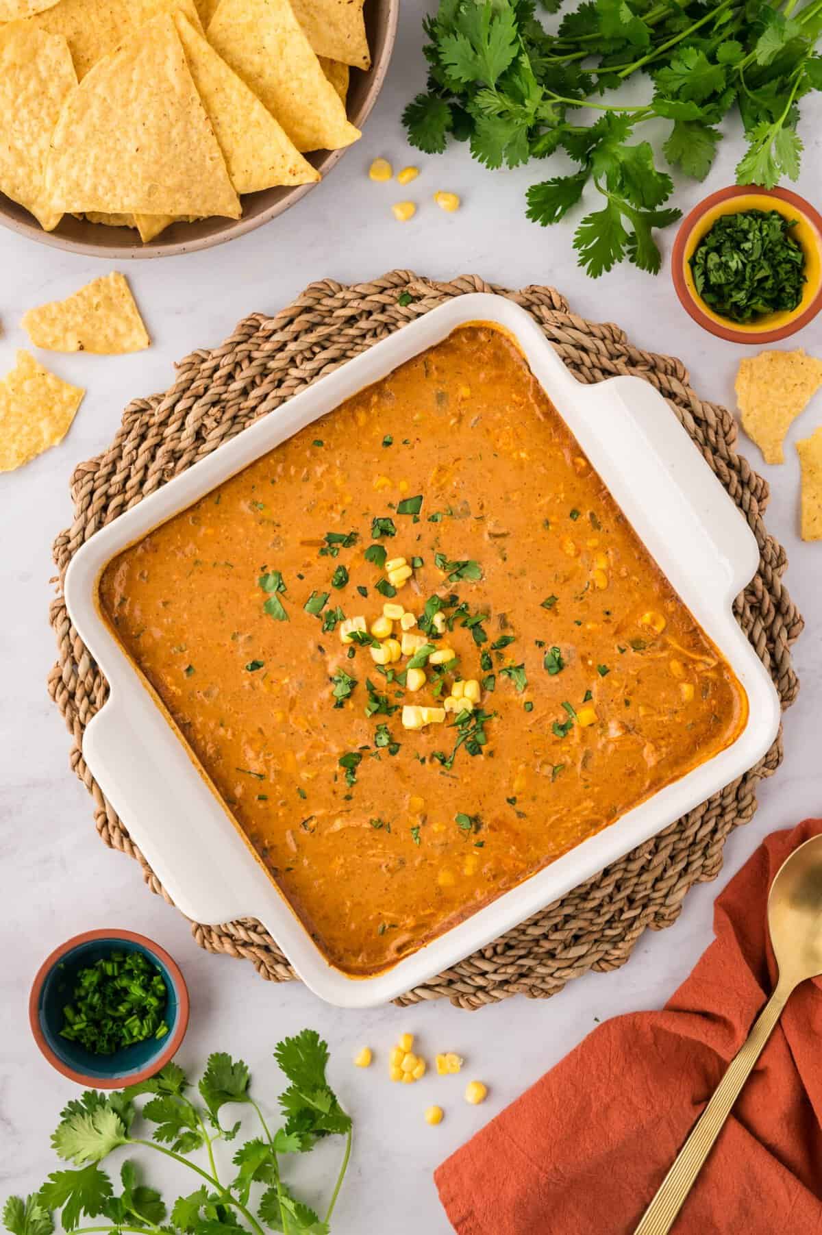 Chicken enchilada dip in white baking dish topped with extra corn and cilantro.