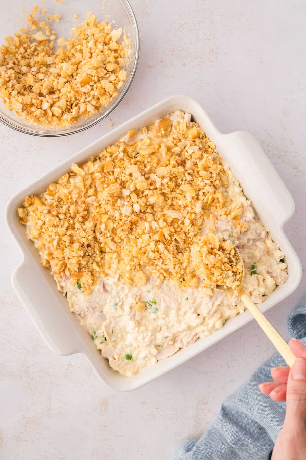 Crackers being spooned over casserole.