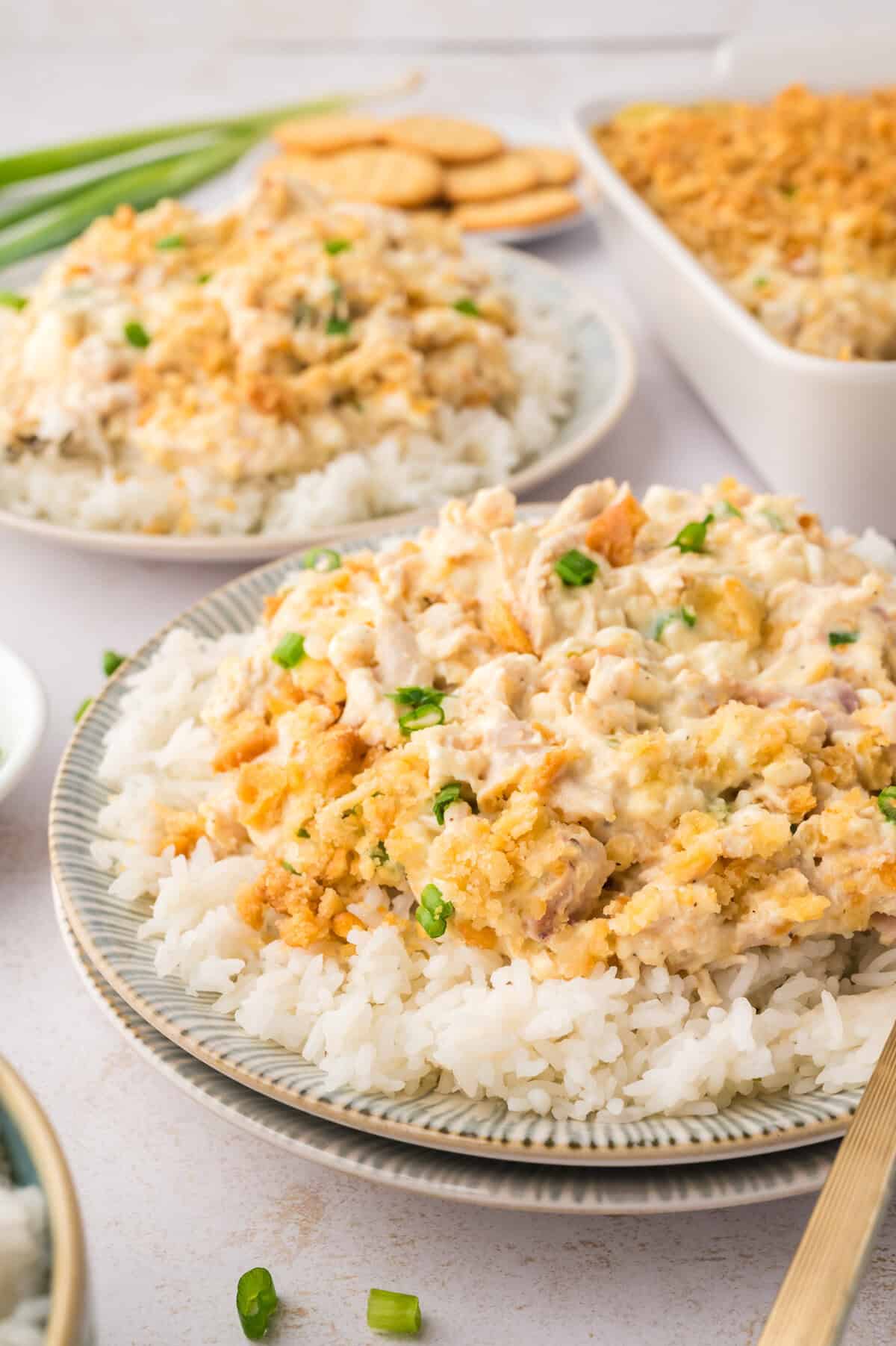 Million dollar chicken casserole over a bed of rice on small plate.